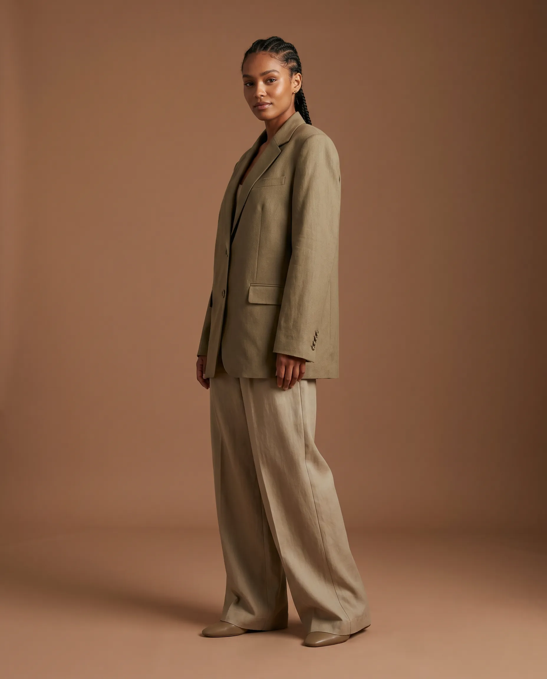 AI-generated on-model fashion photograph: a named AI model wearing a structured garment in a directed three-quarter pose against a warm studio scene, the on-model output Pebblely's core tool does not produce