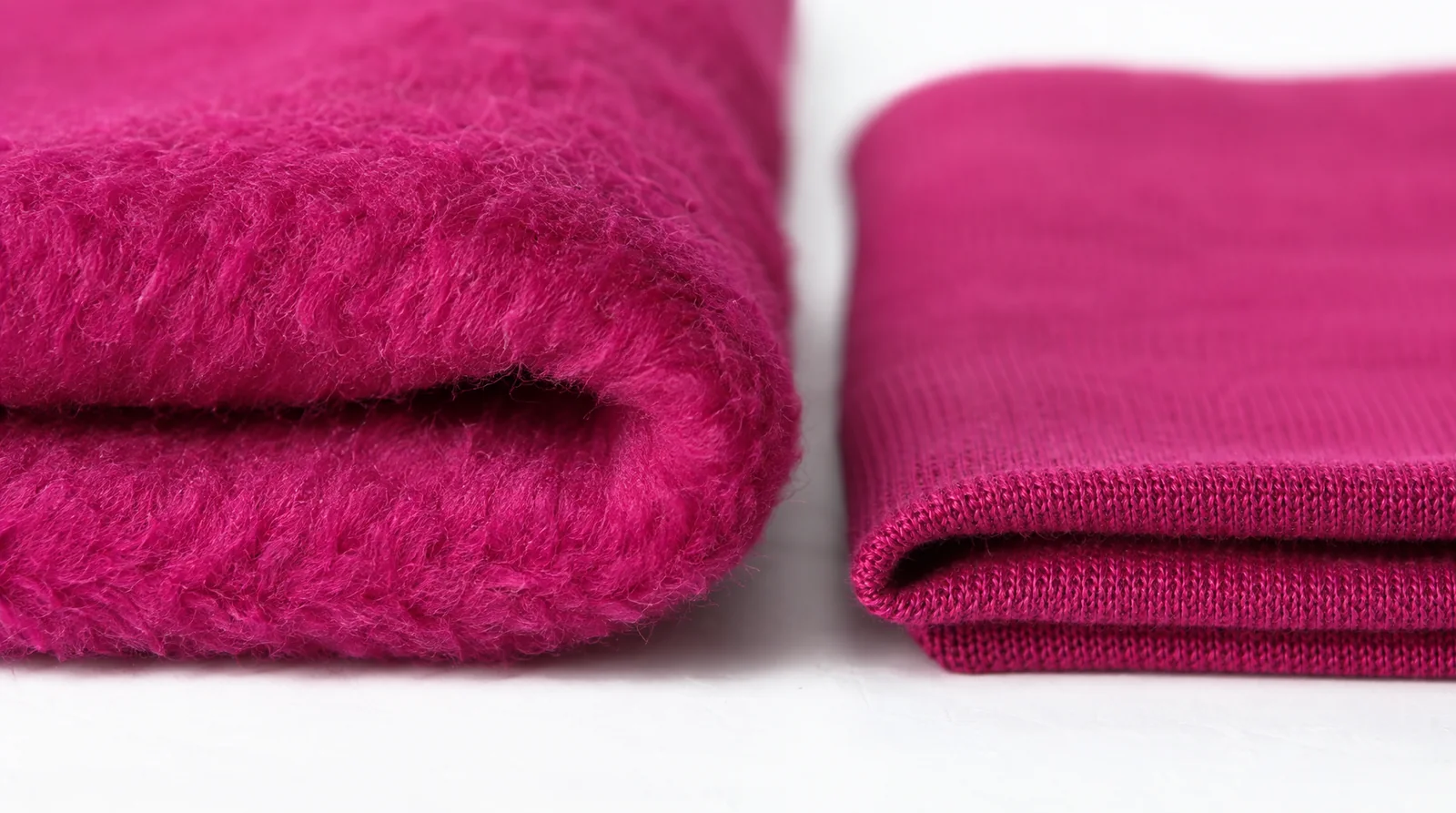 Macro photograph of a folded magenta fleece beside a folded single jersey, showing the difference in loft