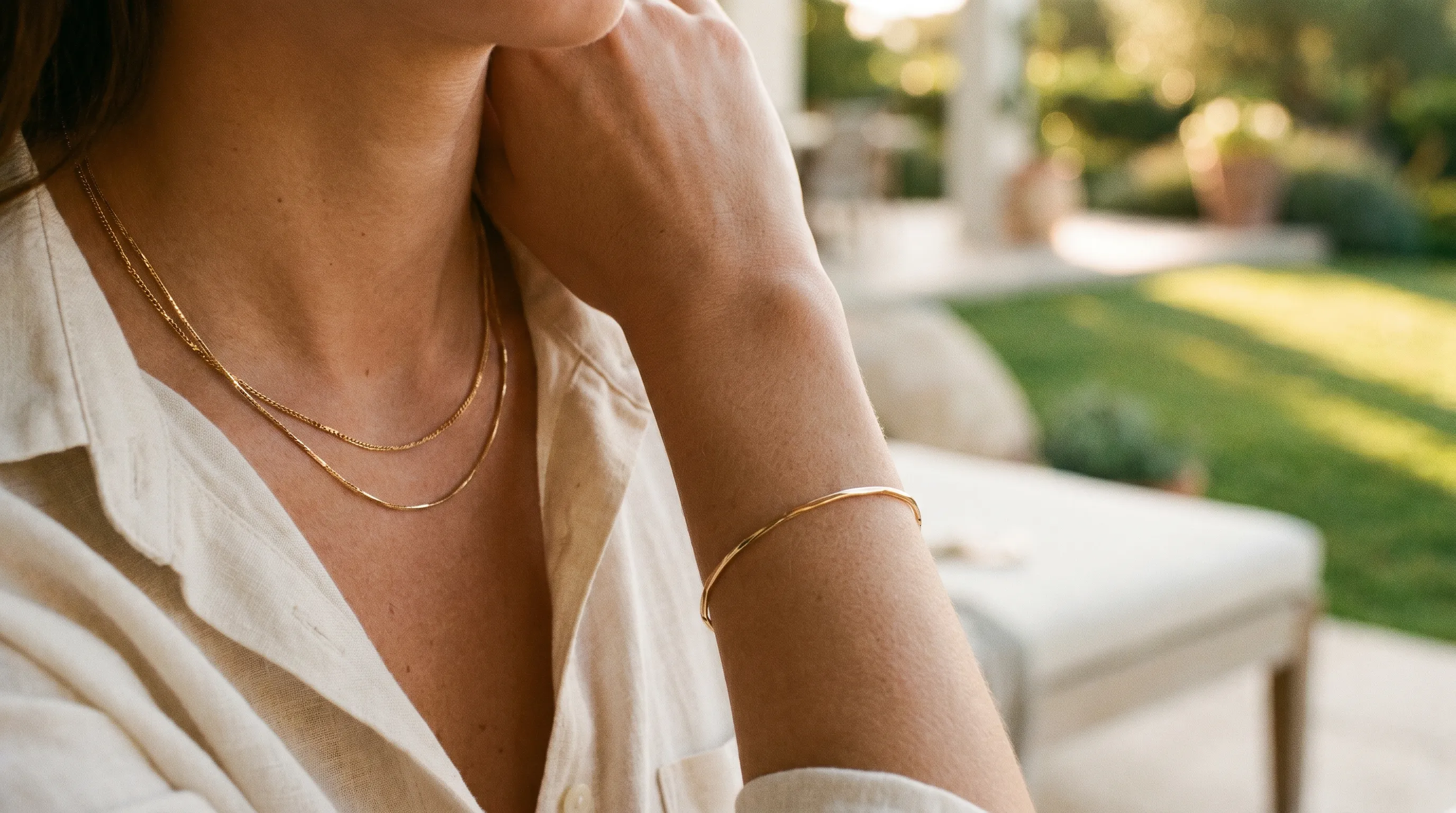 AI-generated lifestyle jewelry frame: a gold layered necklace and matching bracelet on a model in soft golden-hour light against a warm out-of-focus background, editorial mood for social