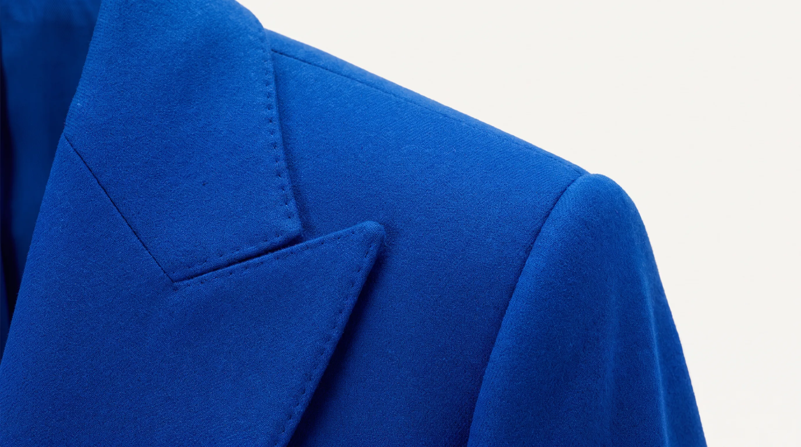 Macro detail of tailored jacket construction — canvas, shoulder structure, and hand-finished seams under raked directional light